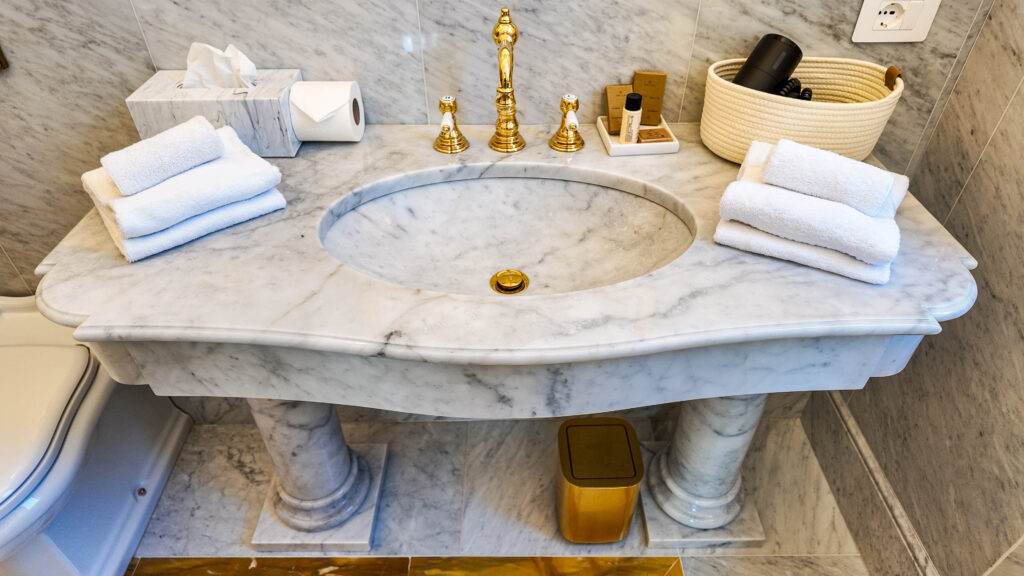 Lavabo in marmo su colonne con rubinetteria dorata
