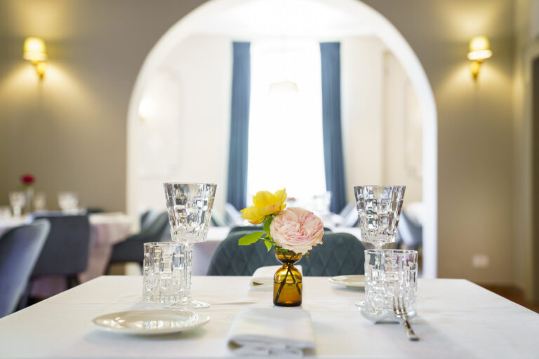 A set table in the foreground and the dining room beyond the arch