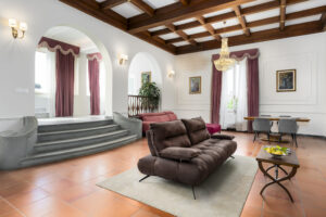 Imperial Suite di Villa L'Avvenire a Siena: salone con soffitto a cassettoni in legno, lampadario di cristallo e divano