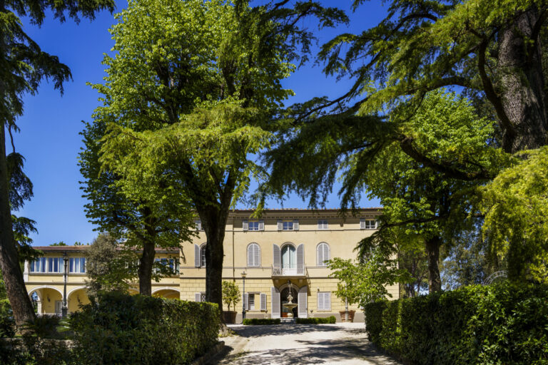 The façade of Villa L'Avvenire framed by the park's cedars