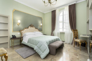 Camera Deluxe Square View di Villa L'Avvenire a Siena: letto con testiera dorata e lampadario