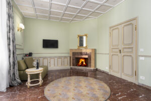 Suite Prestige con Balcone: il camino acceso e la poltrona dell'angolo salotto