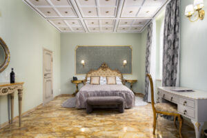 Suite Prestige con Balcone di Villa L'Avvenire a Siena: letto con testiera dorata, scrivania e soffitto a cassettoni