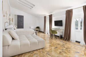 Camera Deluxe Park View di Villa L'Avvenire a Siena: zona giorno con divano, scrivania e finestre sul parco